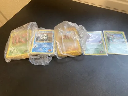 Three bagged bundles of cards and two sleeved single cards on a dark desk.