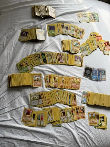 Many sorted stacks of cards spread out across a bed.